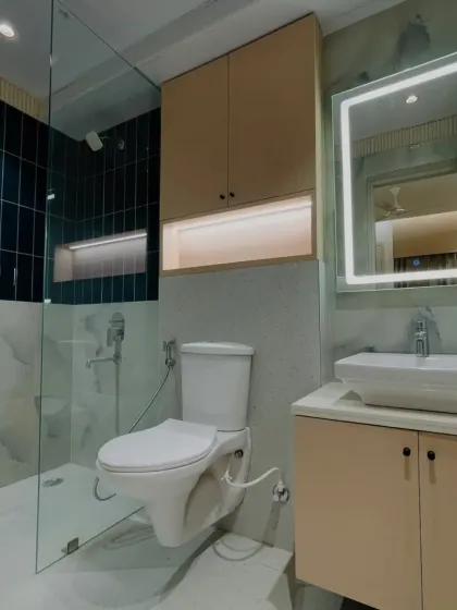 This bathroom features a modern vanity, a backlit mirror, and a glass-partitioned shower area with stylish dark green tiles. It's a perfect blend of functionality and design.