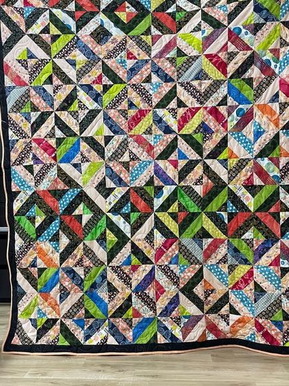 A complex and dynamic quilt made entirely of half-square triangles in a multitude of colors.