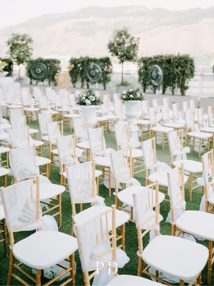 The elegant guest seating for the rooftop Haldi, with white and gold chairs creating a clean, classic look against the green lawn.