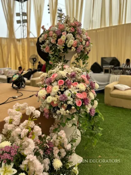 A tower of pastel perfection. These tiered floral arrangements in classic white urns add a touch of timeless elegance and romance to the wedding decor.