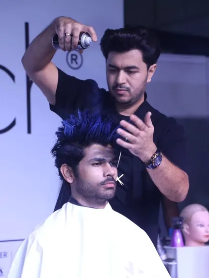 Adding the finishing touches to the men's blue mohawk style. Hairspray is key for locking in these gravity-defying looks.