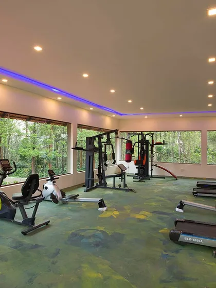 The modern and spacious gym at Coorg Cliffs Resort, offering a variety of equipment for a full workout with a view.