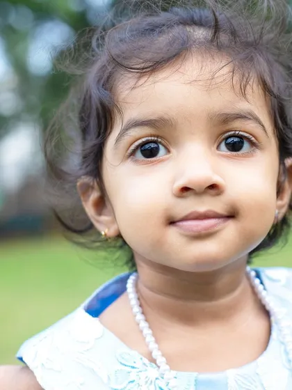 A close-up portrait of a little girl during an outdoor family shoot. The natural background and soft light create a beautiful, classic look.