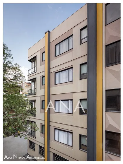 The corner view of the Yellow Line Apartment facade, showing how the design wraps around the building. The composition of windows and solid panels was planned to maximize light while maintaining privacy.