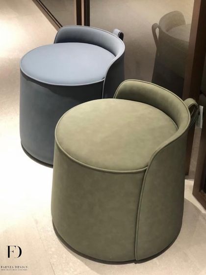 A pair of versatile, modern poufs, one in olive green and one in grey. The integrated backrest and handle detail make them both comfortable and easy to move around as needed.