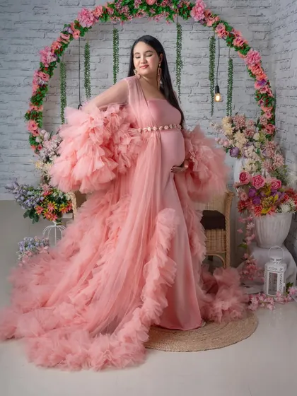 A graceful pose in our popular pink ruffled gown, set against a romantic floral arch.