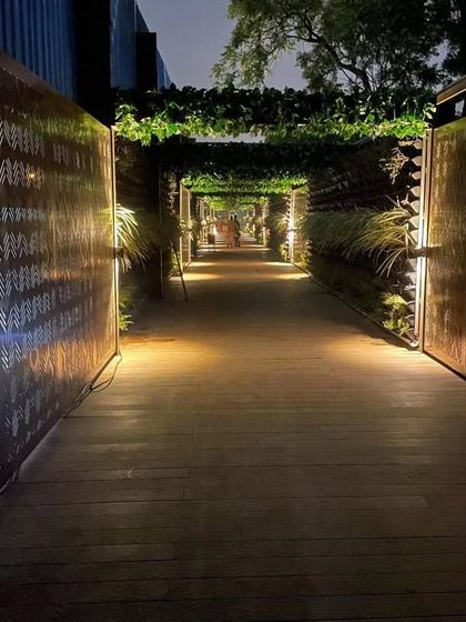 We designed this enchanting walkway for a commercial venue. The path is lined with illuminated, laser-cut metal screens and topped with a canopy of green vines, creating a magical entrance.