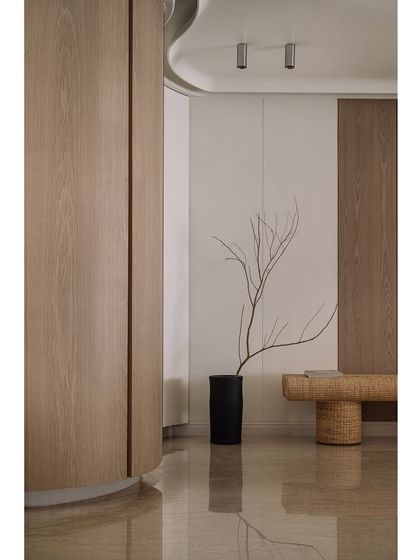The entrance corridor of Kanso House, where curved wooden walls and a woven bench create a welcoming and organic first impression.
