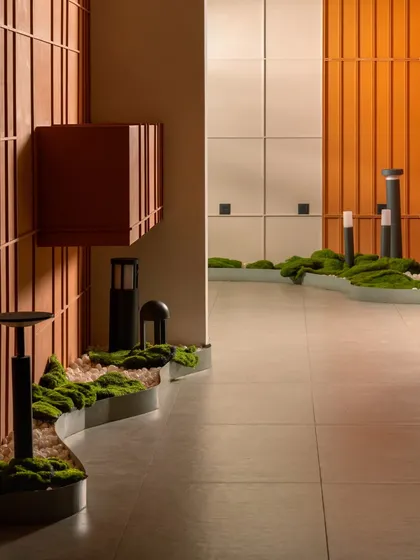 For this lighting showroom, the goal was to let the products shine. We created a clean, gallery-like space using a neutral palette, then introduced organic elements like this curved moss bed and bold terracotta paneling to guide the eye and add warmth.