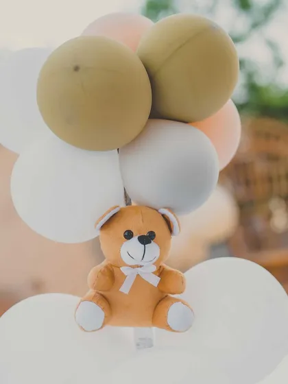 A cute detail from the teddy bear themed baby shower, with a small teddy bear attached to a cluster of balloons.