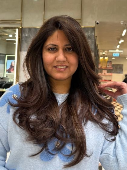 A happy client showing off her new mocha brown hair. The color perfectly complements her skin tone, and the style is fresh and modern.