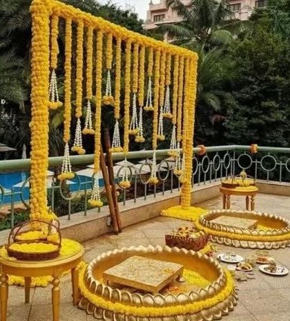 For this terrace Haldi, I built a frame with hanging marigold and jasmine garlands. The setup includes traditional brass platters for the ceremony rituals.