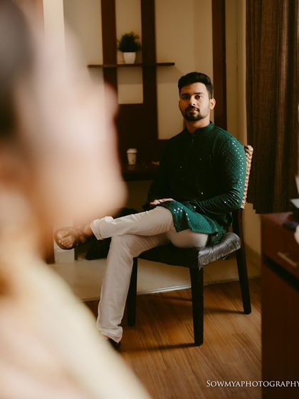 An over-the-shoulder shot of the groom during a pre-wedding session. The shallow depth of field creates a sense of intimacy and anticipation.