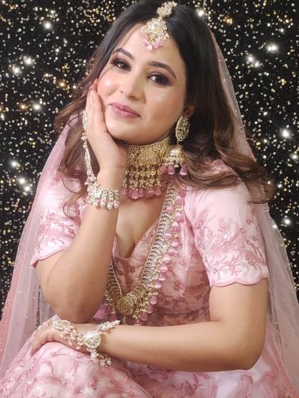 A complete bridal look in pastel pink. The model is wearing a matching pink-beaded choker and layered necklace set, complete with hathphool.