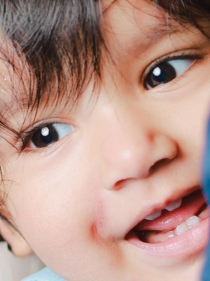 An extreme close-up capturing a baby's bright eyes and first tiny teeth. These detailed shots preserve the little milestones you never want to forget.