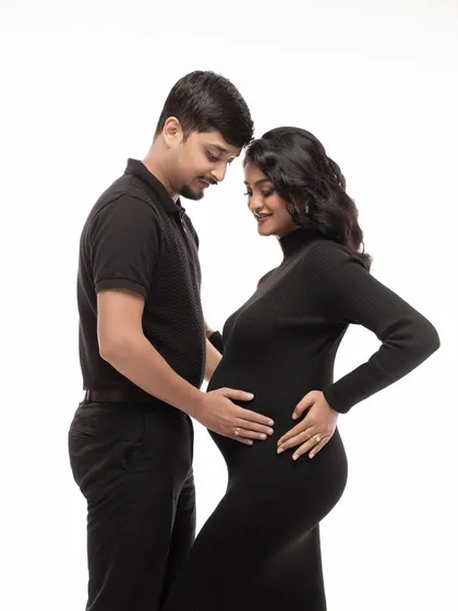 Including your partner is a wonderful way to capture the love and anticipation you share. This classic portrait, with simple black outfits against a clean white backdrop, focuses purely on the connection and tenderness between the expecting parents.