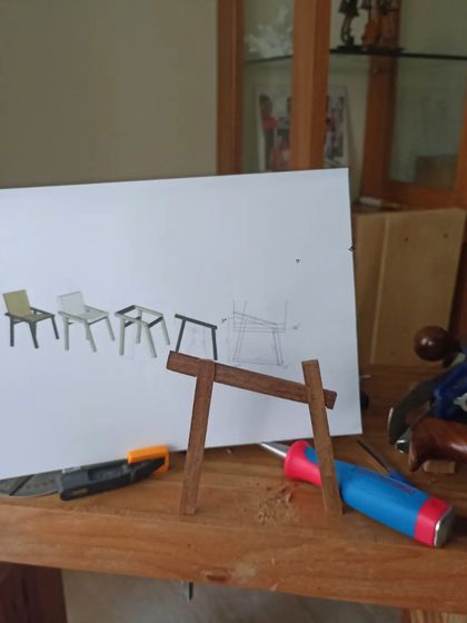 The first parts of the chair model's leg assembly, with the design reference in the background. Prototyping is a crucial step in custom furniture design.