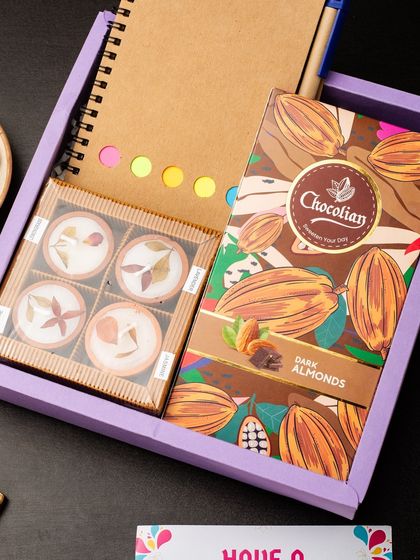 This hamper is perfect for the organized professional. It combines an eco-friendly notebook with sticky notes, a pen, and a box of dark almond chocolates and chocolate-coated nuts, blending productivity with indulgence.