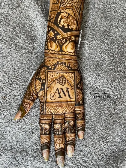 A bold and beautiful back-of-hand design with the initials "AM" as the centerpiece. The monogram is surrounded by swans and elephant motifs.