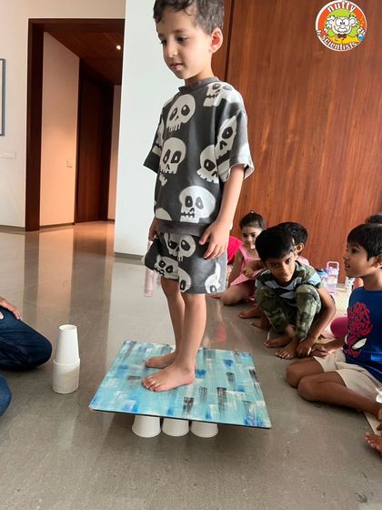 One child carefully tests the strength of the paper cup structure. This experiment is a great lesson in physics, patience, and trusting the science.