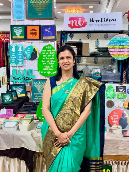Me at my stall, ready for another day at the exhibition. The display is full of colorful frames, magnets, and wall hangings.