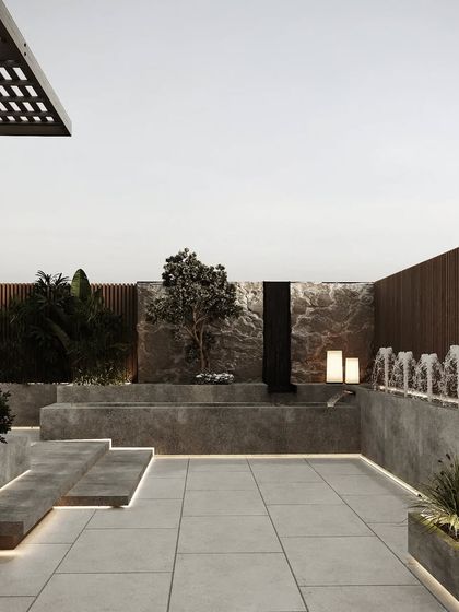 A serene rooftop design featuring a minimalist water feature and sculptural elements. The use of concrete and natural stone creates a modern, zen-like atmosphere.