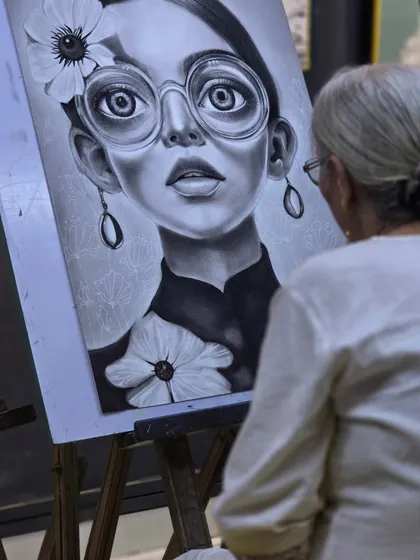 Another angle of the artist at her easel, showing the large scale of the charcoal drawing and the dedication it takes to complete such a detailed piece.
