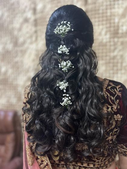 A simple yet elegant open hairstyle. This look features a twisted half-updo with soft curls, adorned with small bunches of baby's breath for a delicate and romantic touch.