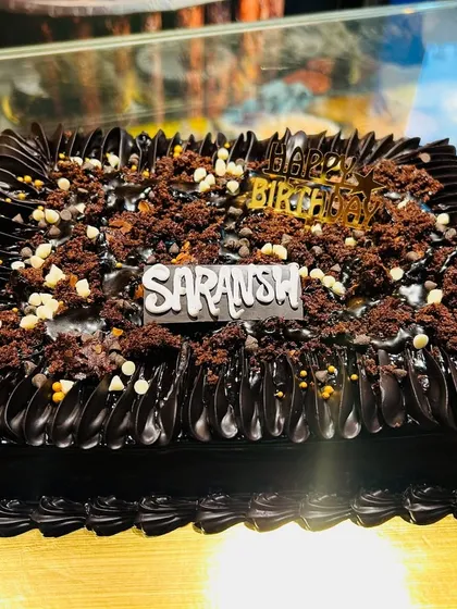 A delicious-looking square chocolate cake topped with chocolate crumble and white chocolate chips.