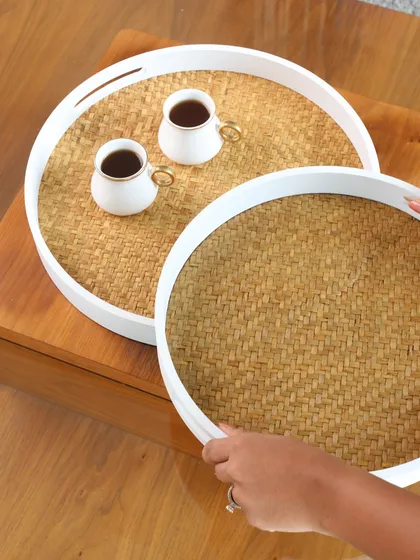 Our round woven trays with a clean white rim. This modern take on a classic design is perfect for a coastal or minimalist home, ideal for serving coffee or as a simple centerpiece.