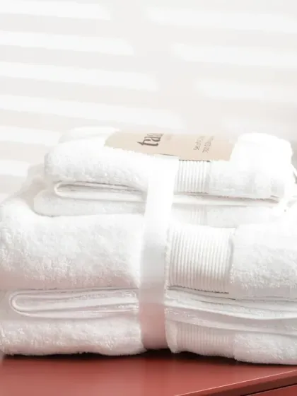 A stack of white towels on a different colored surface, showing versatility in styling. The bright, clean look is perfect for home and bath products.