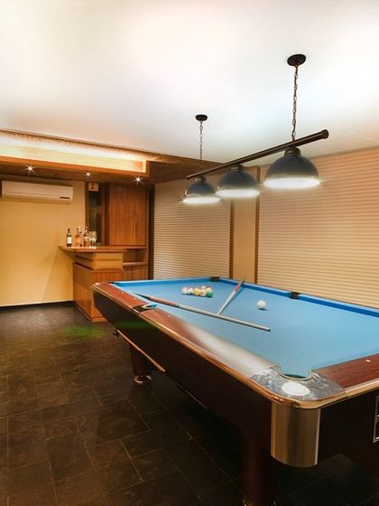 This entertainment room features a classic pool table, a built-in wooden bar, and warm, focused lighting. It's a dedicated space we designed for leisure and socializing with friends and family.