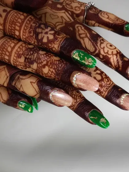 This angle highlights the contrast between the bold green and the soft, shimmery neutral polish, all complementing the bridal henna.