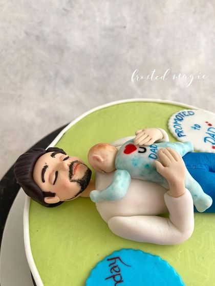 A closer look at the "Promoted to Dad" cake topper, showing the sweet interaction between father and baby.
