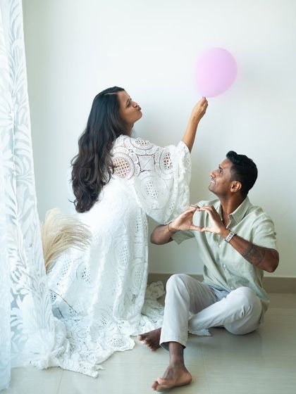 A playful and creative shot announcing it's a girl. The pink balloon adds a fun element, while the dad-to-be's heart-shaped hands show his love.