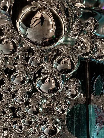 A close-up of the reflective orbs from the 'Silver Escapade' installation. The metallic surfaces create a dynamic, interactive experience, blurring the boundaries between past, present, and future.