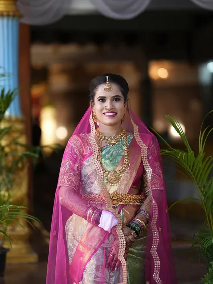 A classic portrait of the bride in her gorgeous silk saree and pink veil, ready for her wedding ceremony.