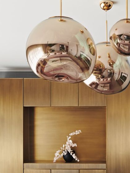A close-up of the rose-gold pendant lights in the Maximum City Duplex. The reflective, sculptural forms add a touch of glamour and serve as a focal point in the living space.
