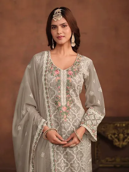 A graceful grey salwar kameez with delicate floral and geometric thread embroidery. The organza fabric and detailed hem on the pants and dupatta add a touch of luxury.