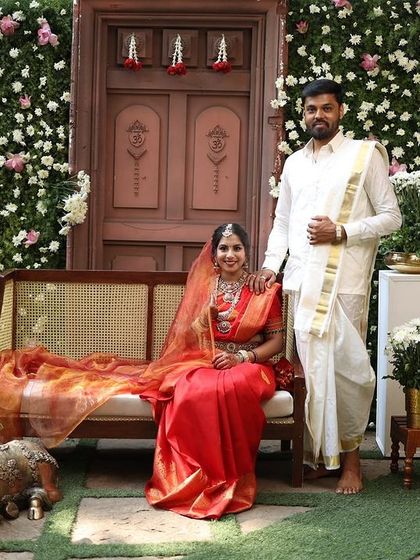 A picture perfect moment. Our bride Supritha and her partner look wonderful against the floral backdrop. Her choice of a multi-layered Victorian-style necklace with Kemp stones adds a unique grandeur to her red bridal saree.