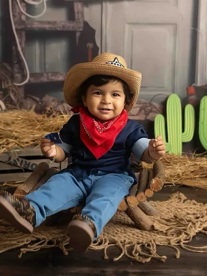 Howdy, partner! This handsome little Texan is ready for an adventure in our cowboy-themed setup, complete with a hat, bandana, and rustic props.