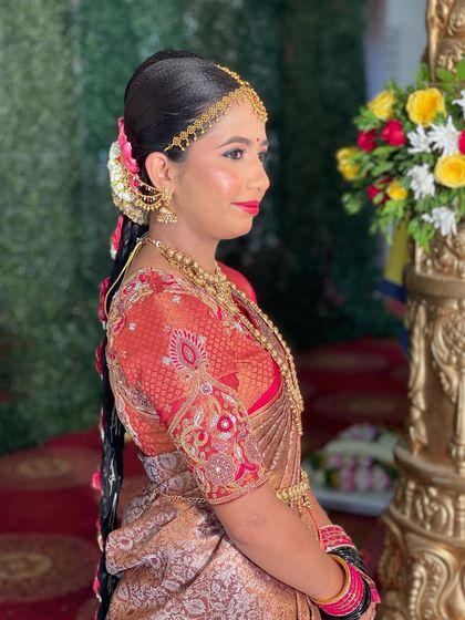 This bride looks absolutely stunning in her Muhurtham attire. The classic red lip and defined eyes are a perfect match for her traditional gold jewellery and embroidered blouse.
