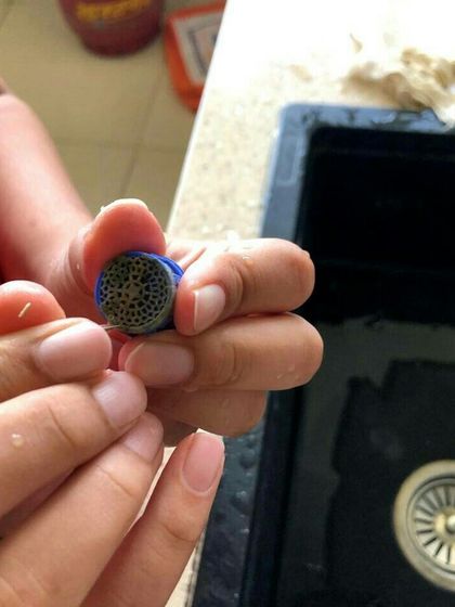 A close up of a student cleaning a faucet aerator. This is a simple but effective way to improve water pressure and conserve water, a key lesson in our plumbing module.