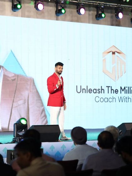Our client on stage in his custom red blazer and white trousers. The vibrant color and sharp tailoring command attention from the audience.