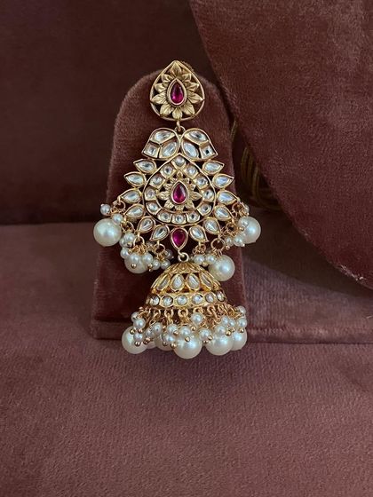 A close-up of a jhumka from the red and pearl kundan set.