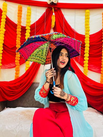 A fun and colorful shot from a Mehendi ceremony, holding a traditional embroidered umbrella. This shows my playful side and love for vibrant accessories.