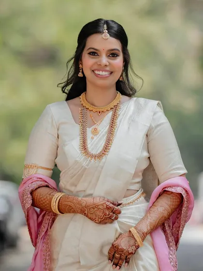 A full-length portrait showcasing the simple elegance of this South Indian bridal look. The makeup is natural and radiant, allowing the bride's happiness to shine through.