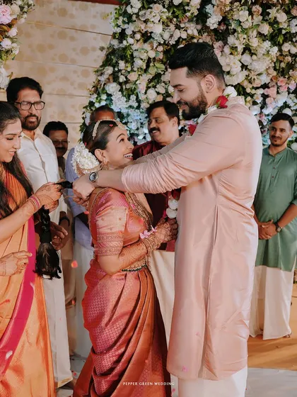 The groom places the garland around the bride's neck, their joyful expressions telling a story of love and celebration.