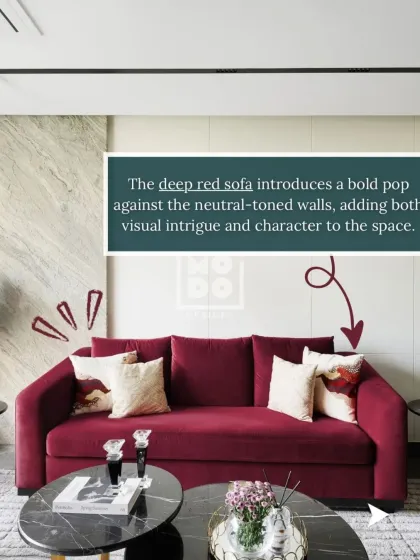 The deep red sofa introduces a bold pop of color against the neutral-toned walls. This single element adds both visual intrigue and a strong sense of character to the space.