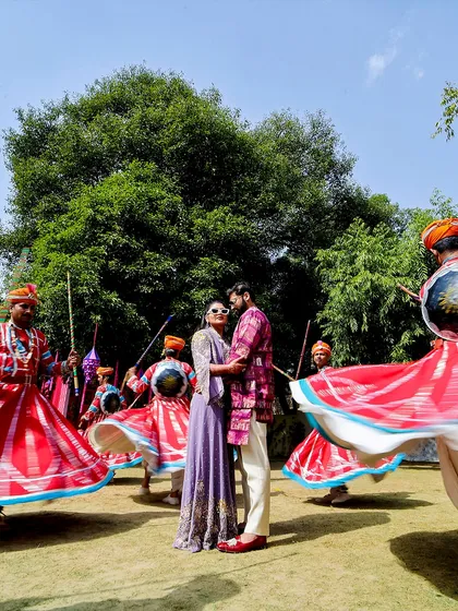 A vibrant and dynamic shot of the couple surrounded by traditional Rajasthani dancers. This photo perfectly blends romance with the cultural richness of the celebration.